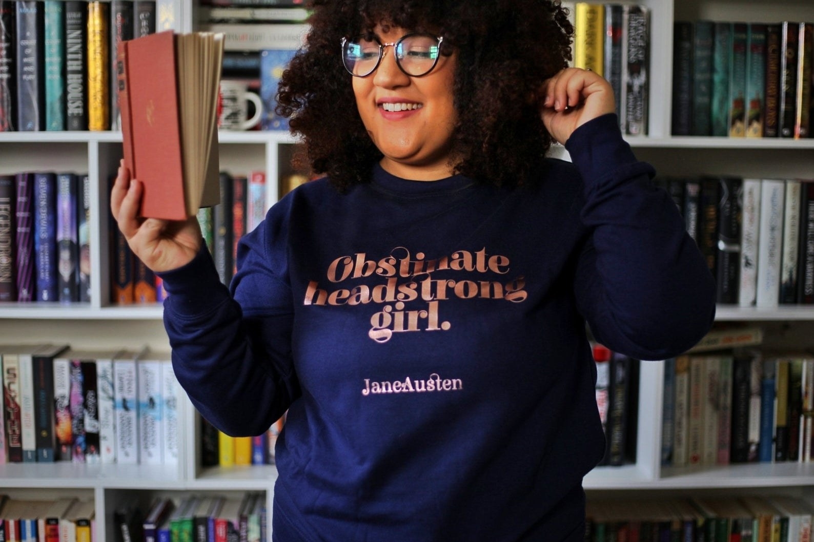 model wearing the navy blue sweatshirt with rose gold text.