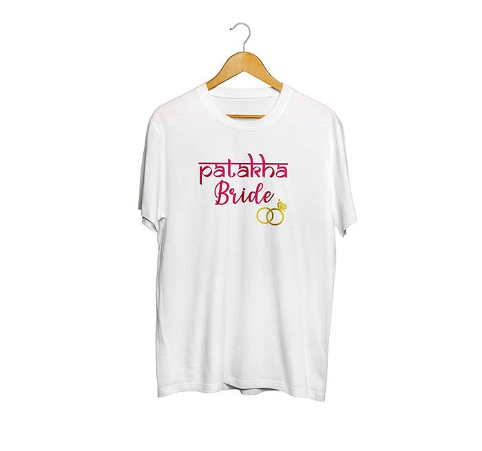 A white tee with the words &#x27;Patakha Bride&#x27; printed on it in pink along with a golden engagement ring