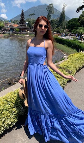 model wearing the blue maxi dress with cut outs and ruffle tier detailing on the skirt