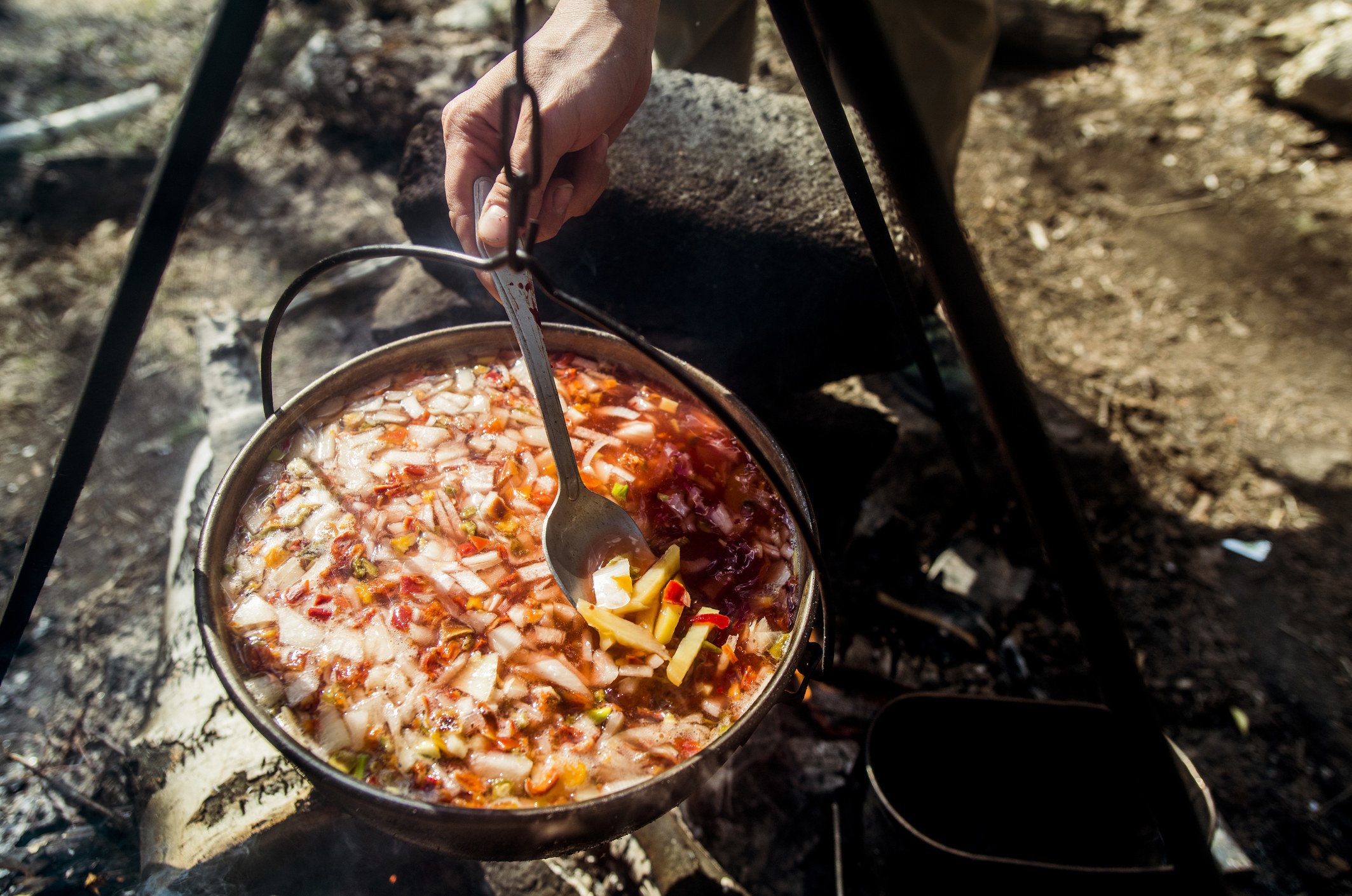 Stirring a pot of soup over a campfire.