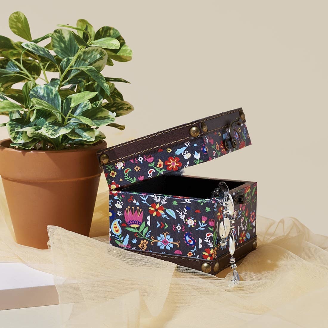 A black cloth storage box with colourful flowers and vines printed on it