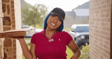 GIF of Megan Thee Stallion waving while delivering a pizza