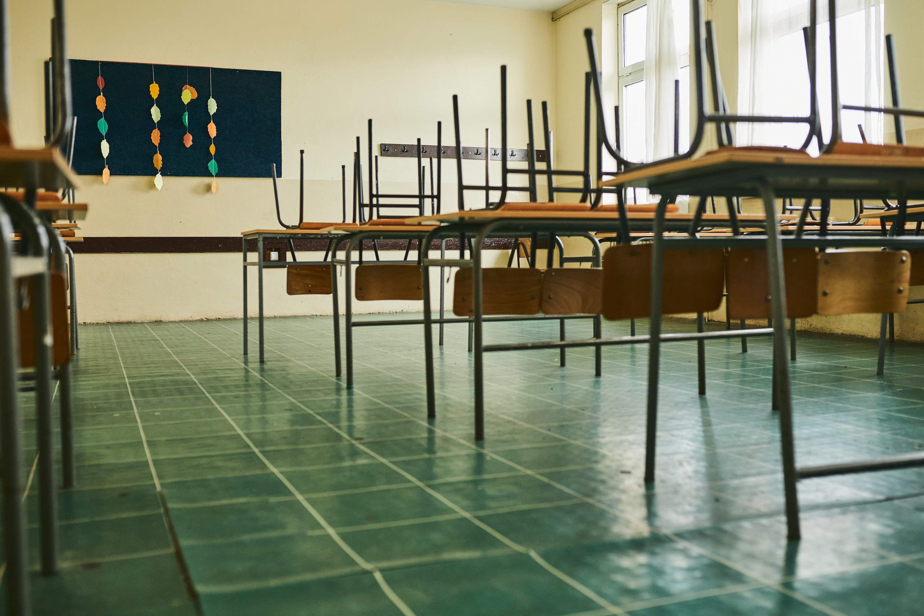 A classroom with the chairs up on the desks