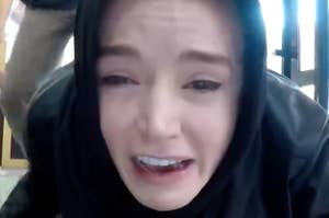European woman wearing a Hijab, looking at a computer screen screaming