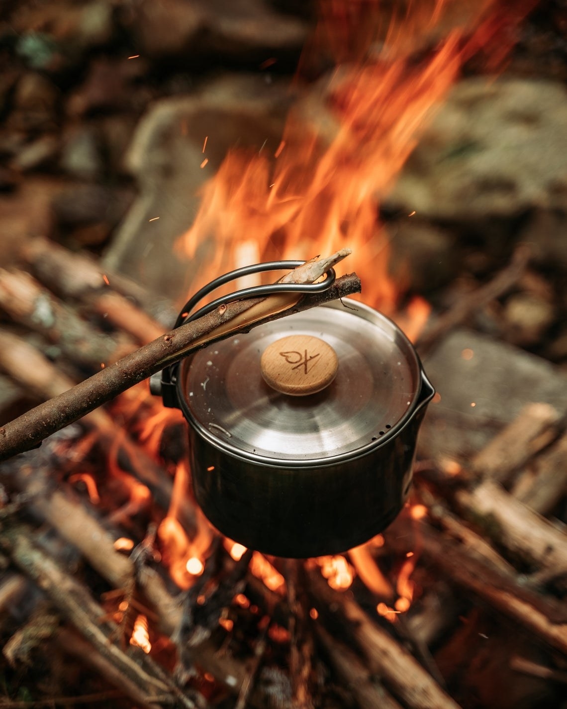 the pot held over a fire with a stick