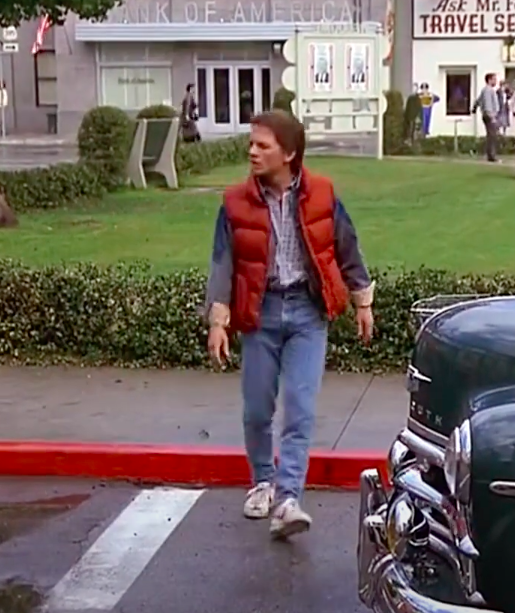 Marty McFly wearing sneakers, jeans, a-t shirt, a button-up, a jean jacket, and a vest