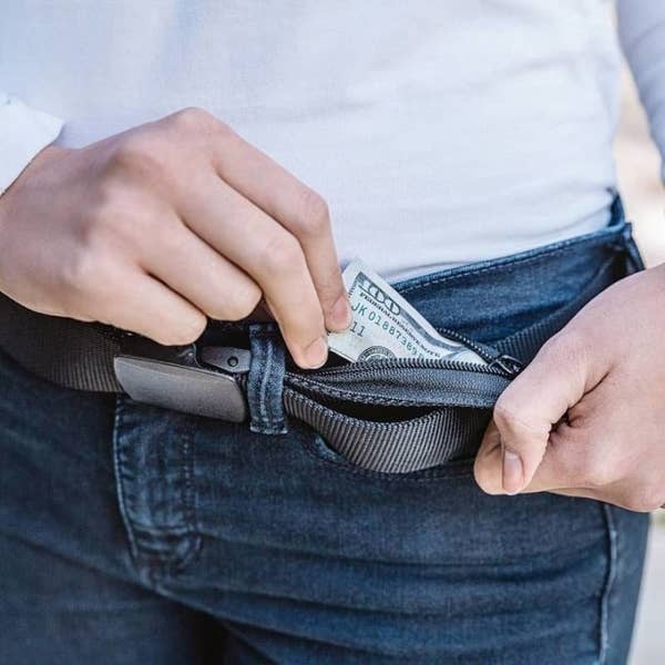 Model putting a $100 bill into the concealed zipper belt
