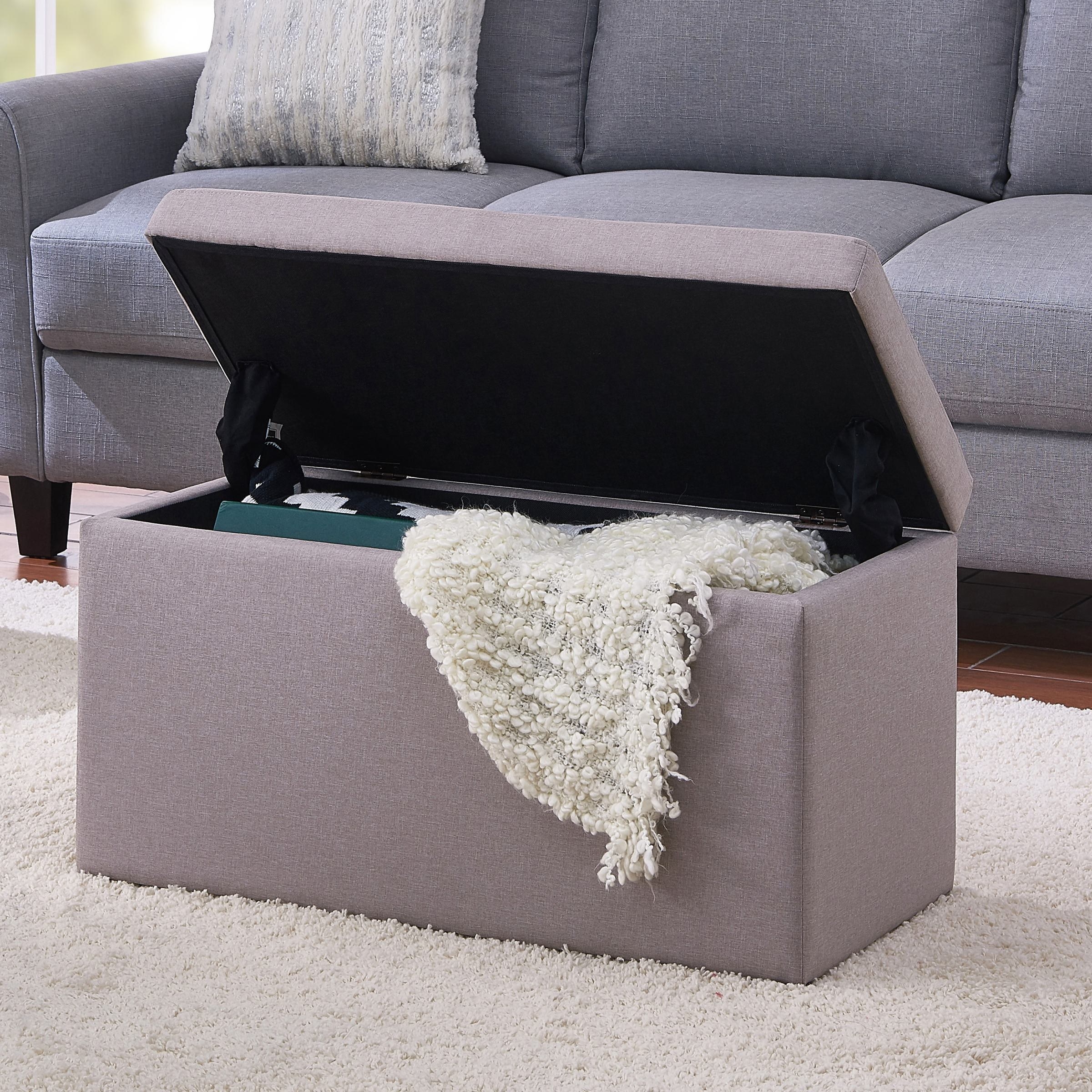 grey storage ottoman with lid open and stuff inside