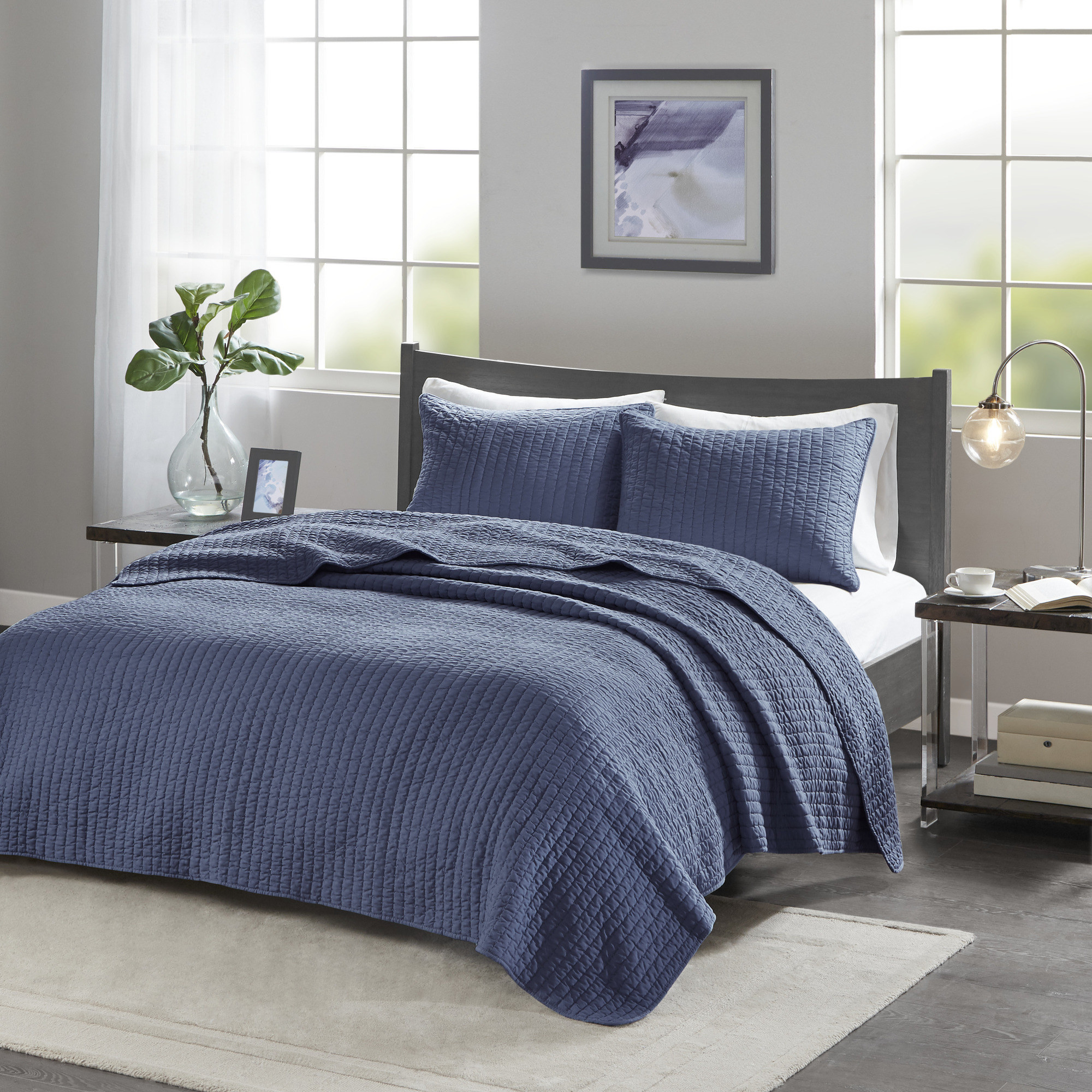 blue coverlet with matching shams on a bed