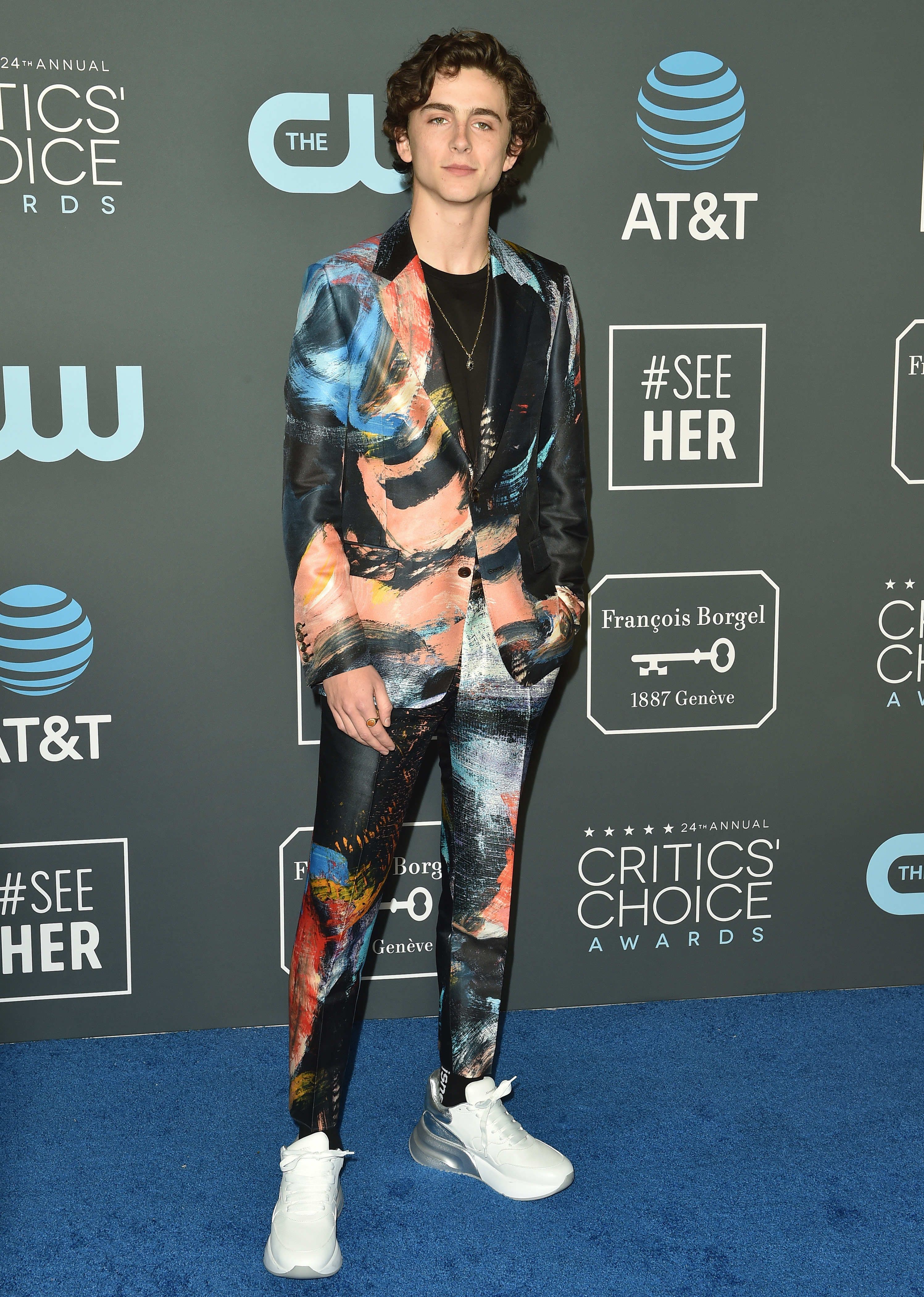 Timothée wears a suit that features colorful paint swipes