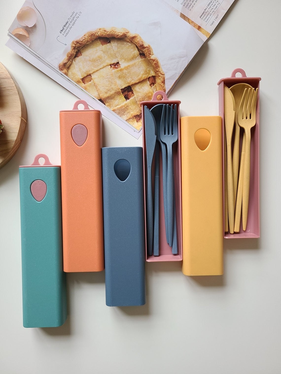 boxes in teal, orange, blue, and yellow; two are open, showing the utensil set