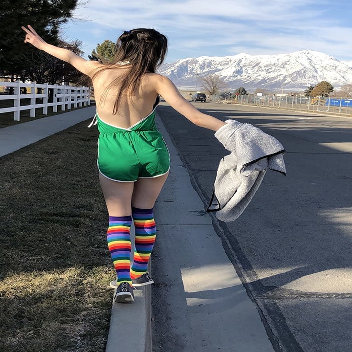 outside, a reviewer walks away from the camera showing the backless back of the green romper