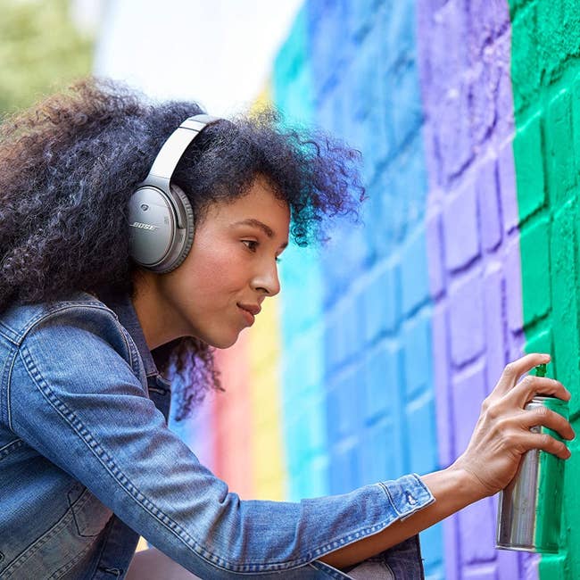 Artist spray painting a wall while wearing headphones