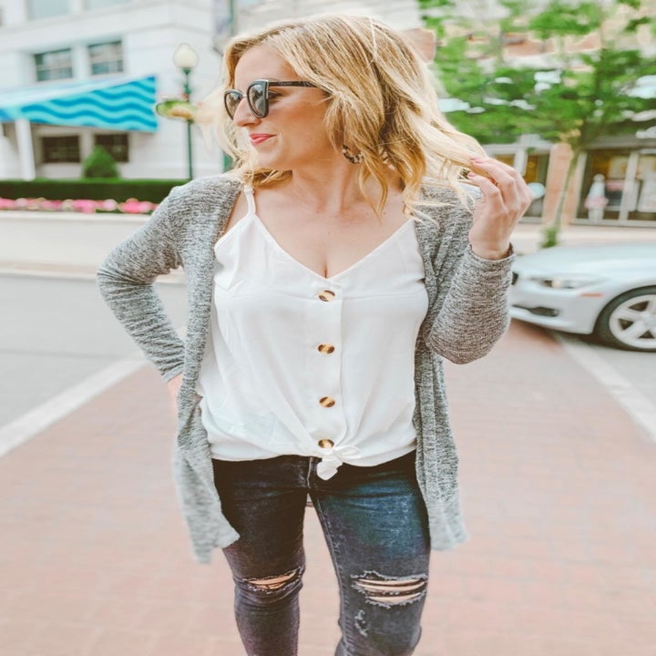 a reviewer photo of someone wearing the top in white with the hem knotted