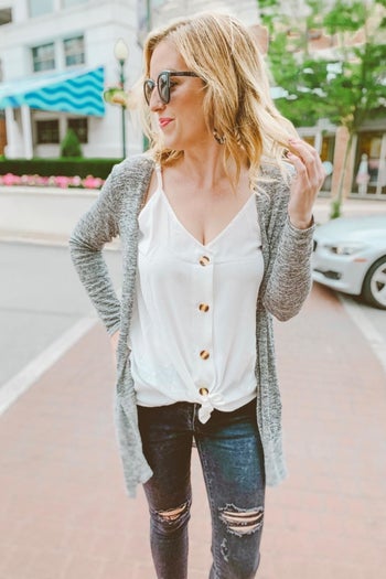 a reviewer photo of someone wearing the top in white with the hem knotted