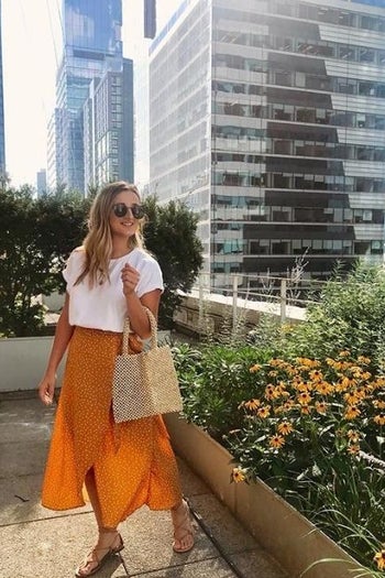 a reviewer photo of someone wearing a white T-shirt and an orange wrap skirt 