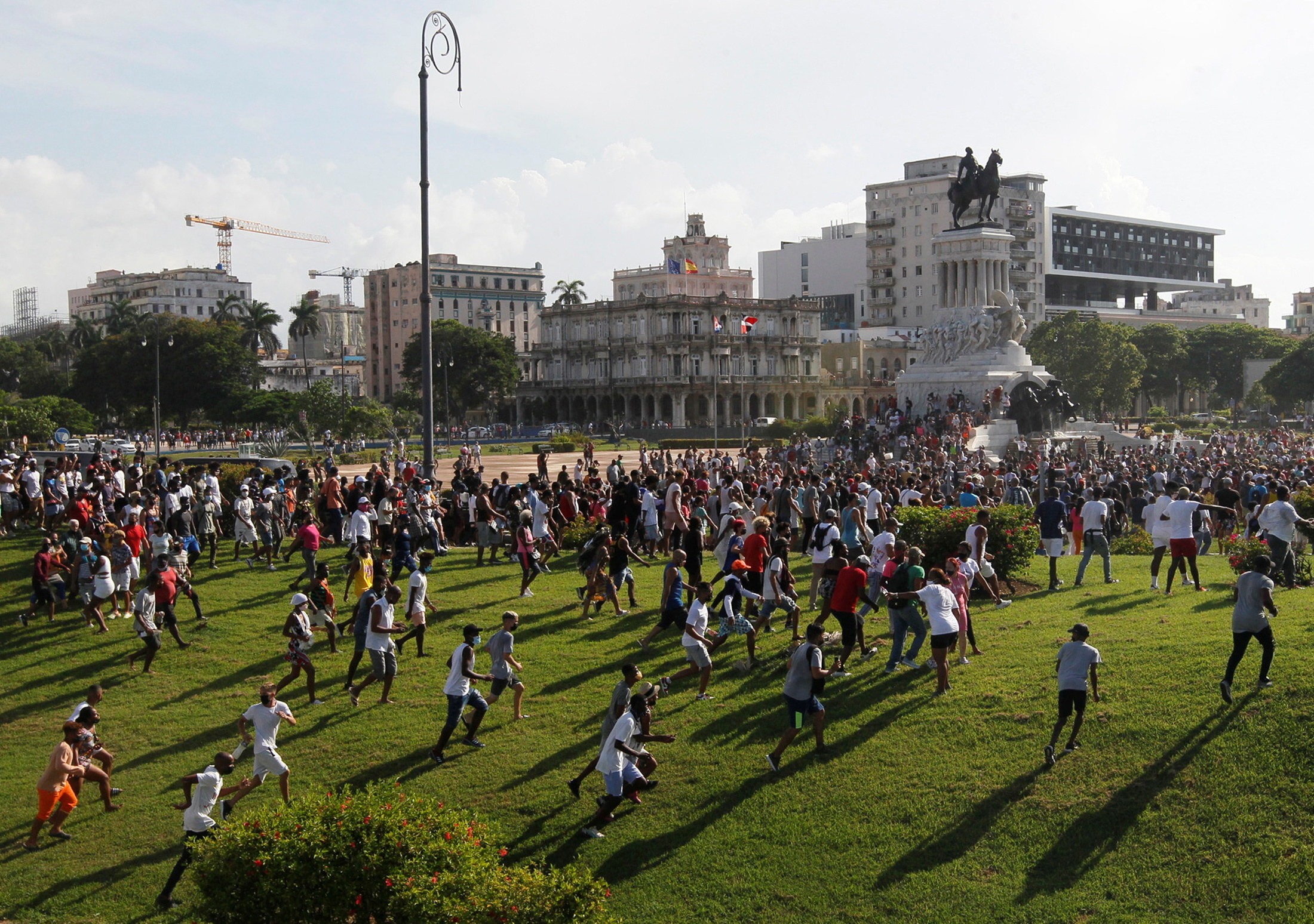 A crowd of people is seen running across the lawn of a government building