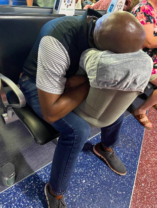 reviewer with their arms inside the hole, holding the pillow in their lap and supporting their head 