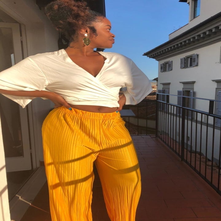 a reviewer wearing the pants in yellow with a white cropped blouse 