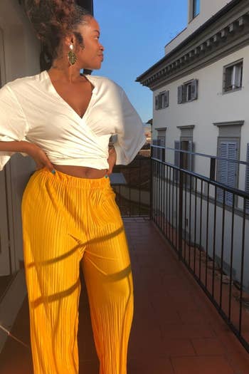 a reviewer wearing the pants in yellow with a white cropped blouse 