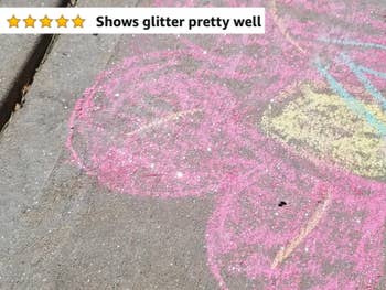 Reviewer's photo showing a pink and yellow flower they drew on the sidewalk using glitter chalk