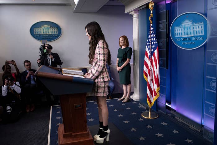 Olivia Rodrigo stands at a lectern in the press briefing room as Jen Psaki looks on