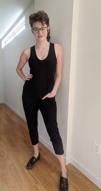 a BuzzFeed writer wearing the sleeveless black jumpsuit with their hand in one of the two front pockets 