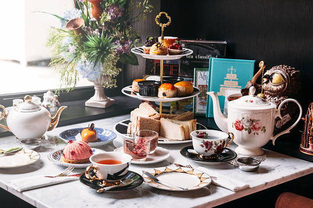 a full table set up for high tea with pastries and finger sandwiches