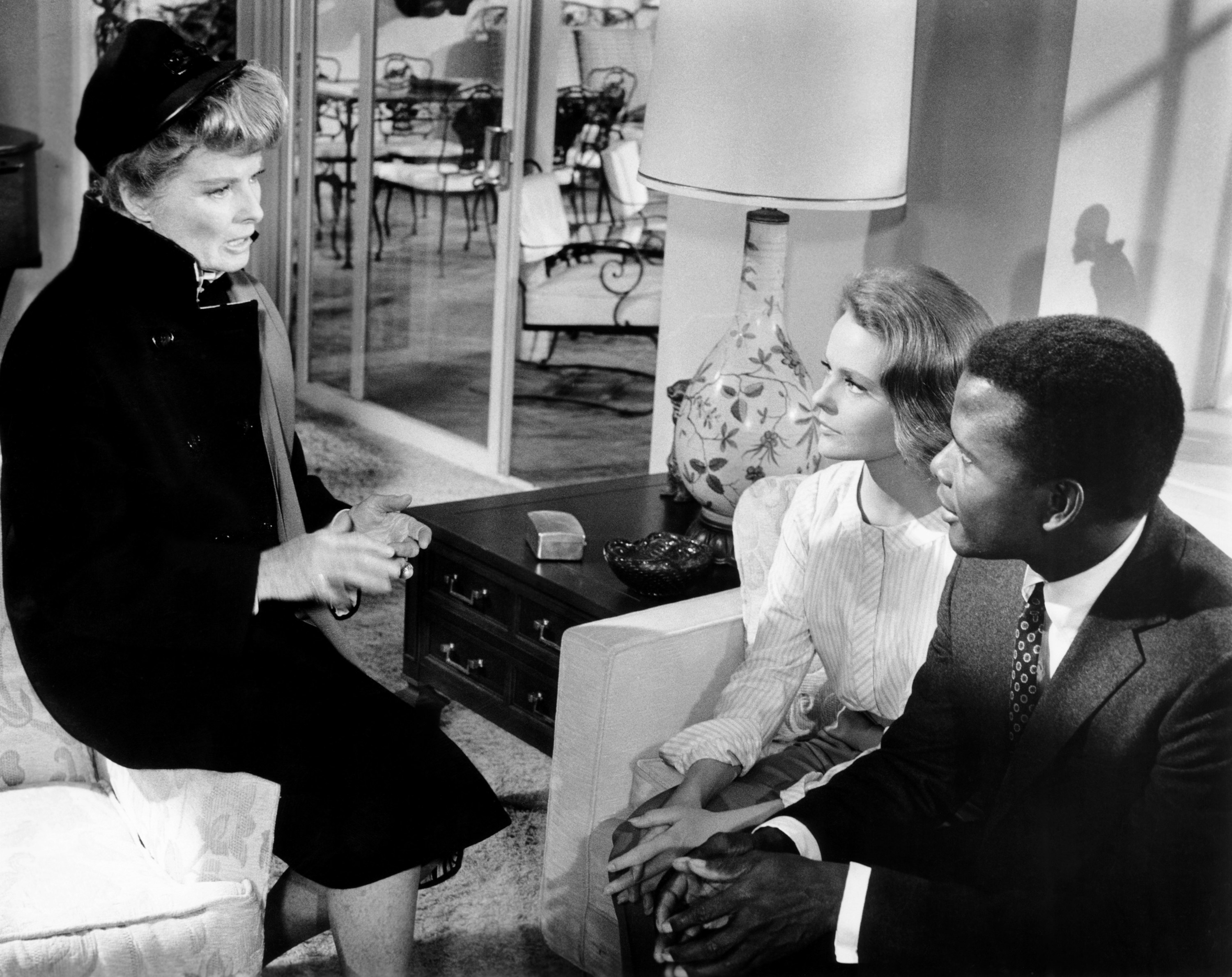 Katharine Hepburn sits on a chair talking to Katharine Houghton and Sidney Poitier on a couch