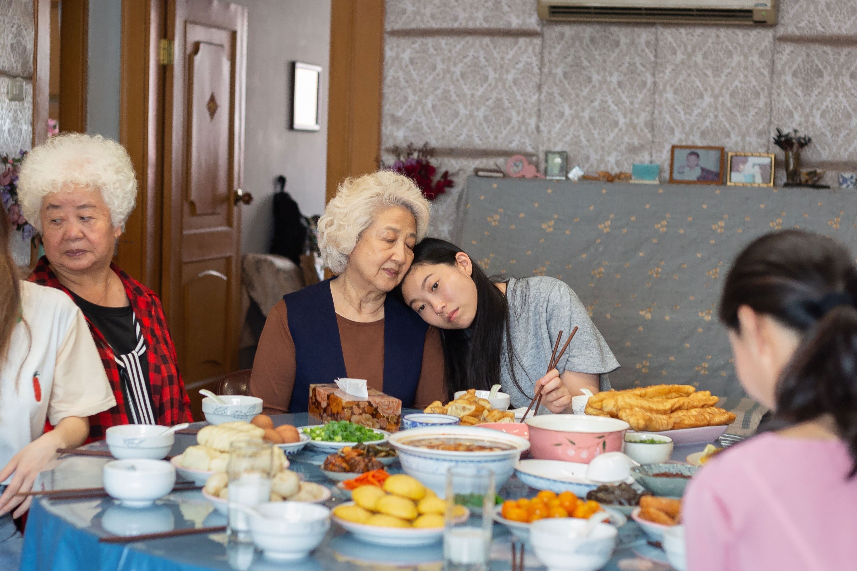 Awkwafina leans on Zhao Shuzhen&#x27;s shoulder at the dinner table