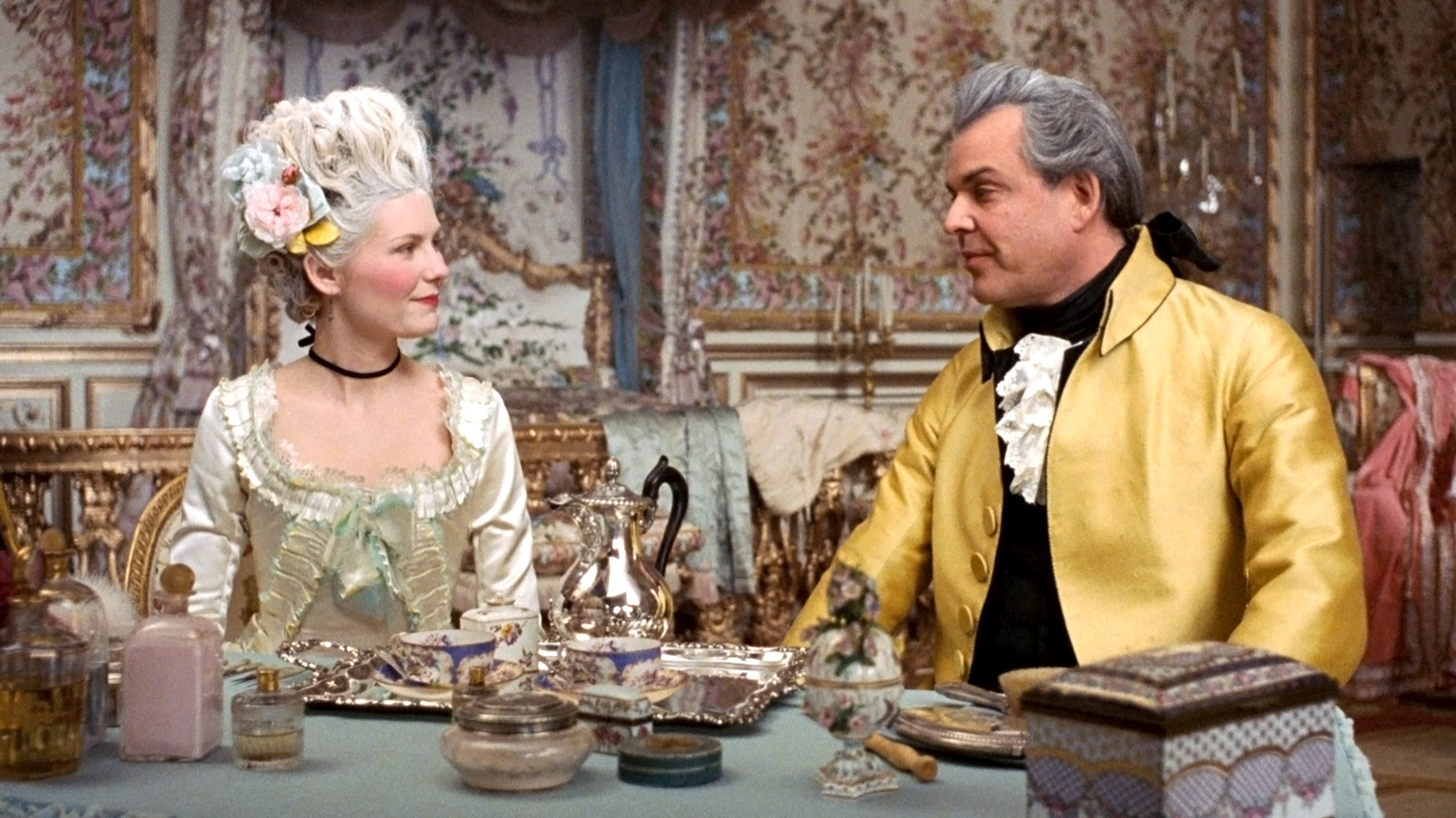 Kirsten Dunst and Danny Huston sit at tea wearing pre-revolution French finery