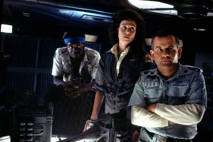 Yaphet Kotto, Sigourney Weaver, and Ian Holm stand in the control room of a space ship