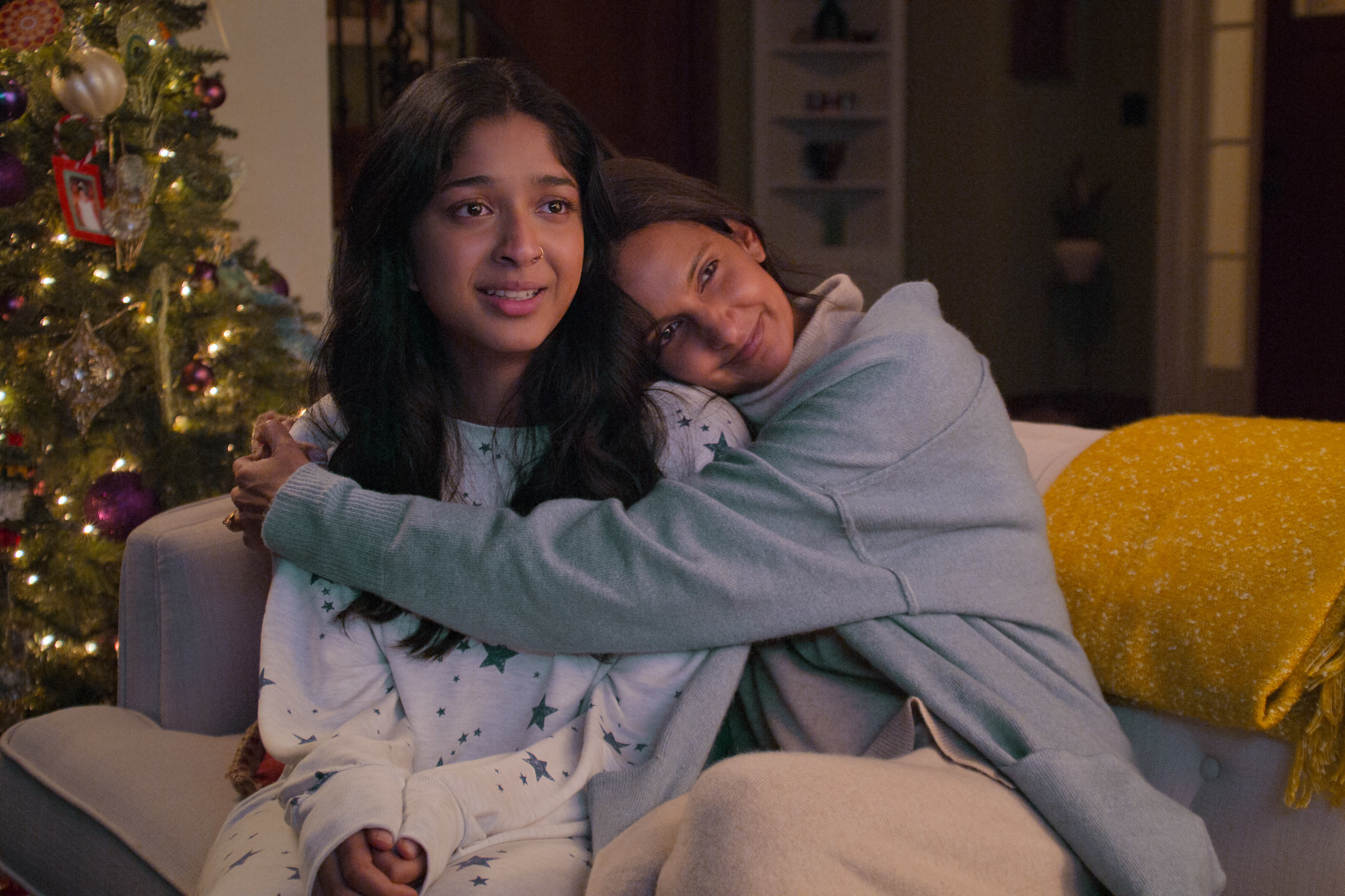 Devi being hugged on the couch with a Christmas tree in the background