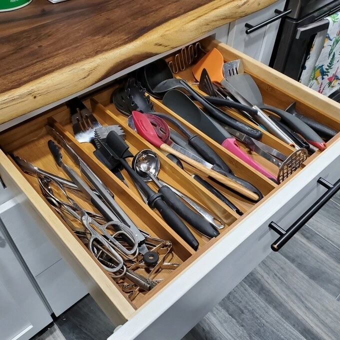 a drawer organizer used to divide a bunch of kitchen utensils