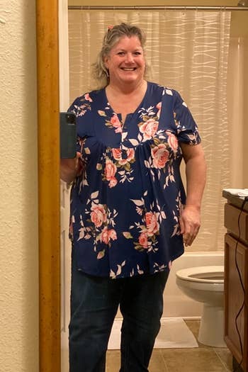 a reviewer wearing the blouse in navy with a pink floral print 