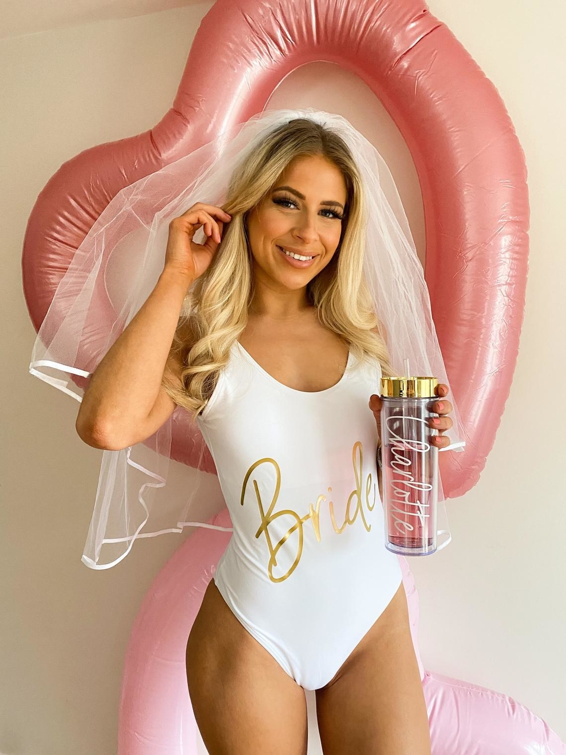 bride wearing a white one-piece swimsuit that says &quot;bride&quot; in shiny gold letters