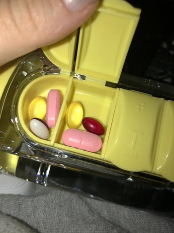 reviewer showing the open pill box at the side of their water bottle