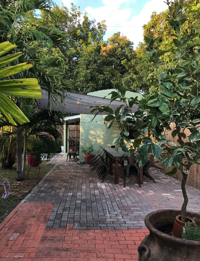 A patio with lots of trees and a little green house