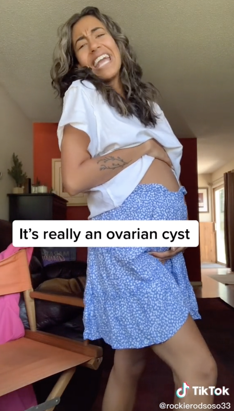 An image of the TikToker clutching her enlarged stomach displaying the cyst