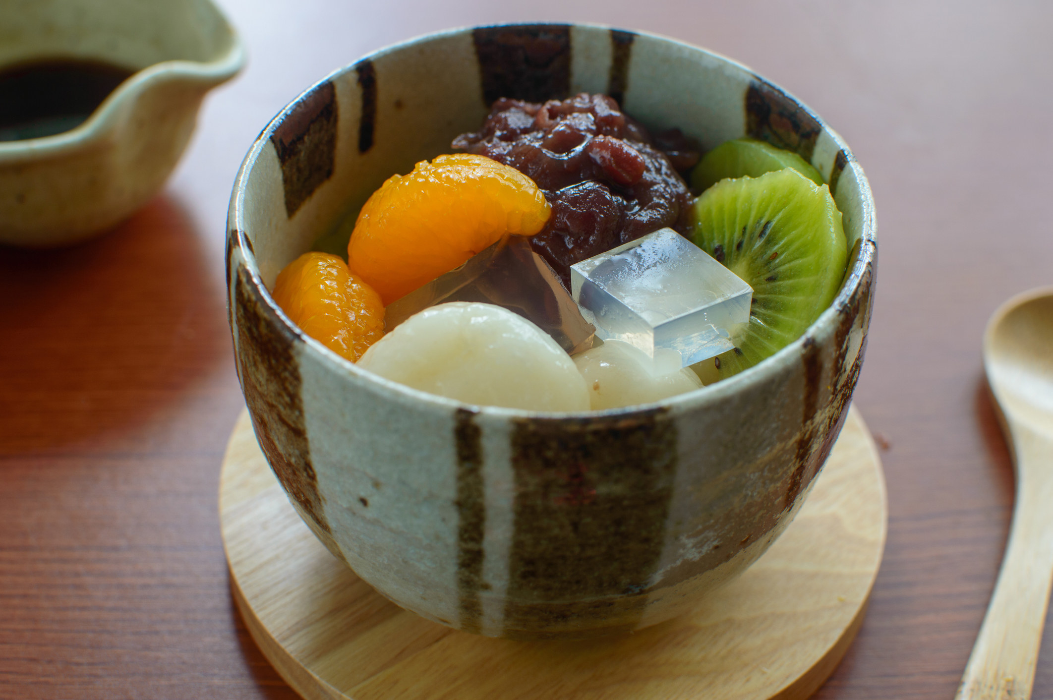 A bowl of small cubes of agar jelly, red bean paste, mochi, and some fruit