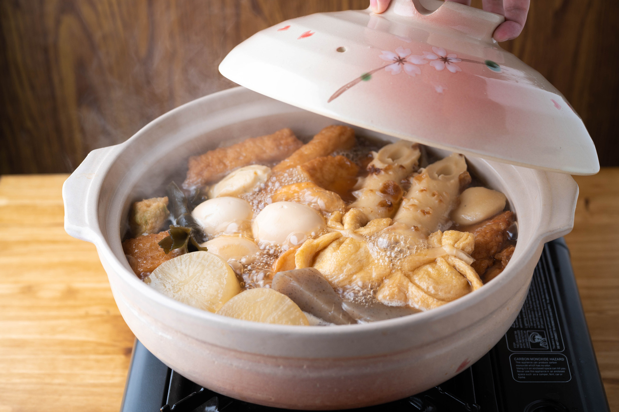 Hot soup in a ceramic bowl that contains various Japanese vegetables and fish cakes