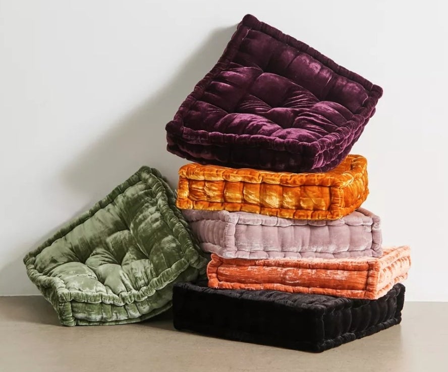 the stack of velvet floor pillows in different colors