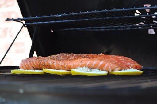 Salmon grilling on a bed of sliced lemons.