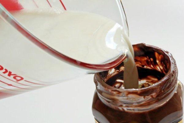 Milk being poured into a Nutella jar.