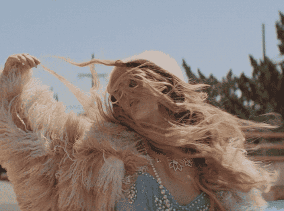A gif of a person dressed in fancy accessories, flinging their hair around