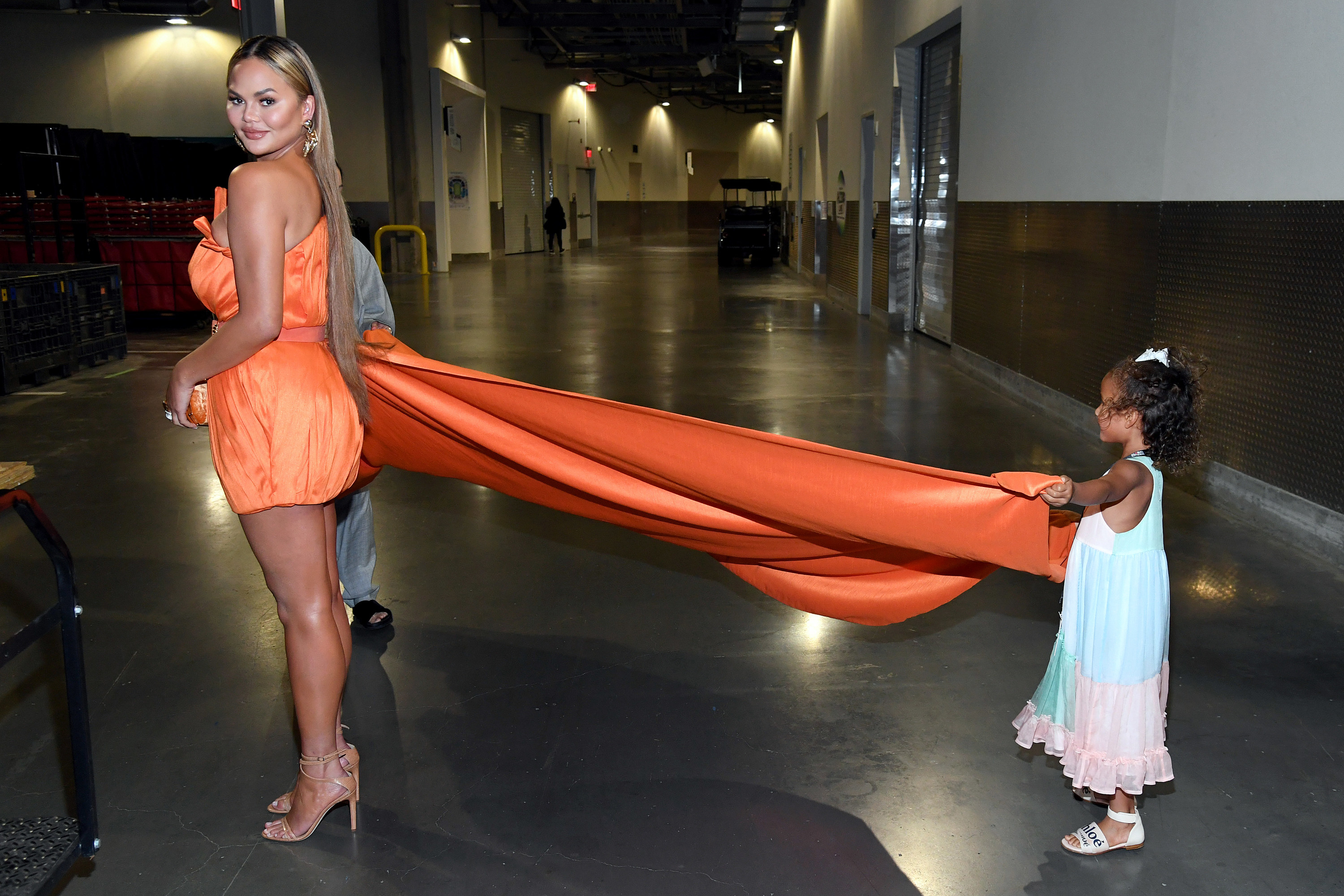 Chrissy standing in a gown as her daughter holds her the dress&#x27; train