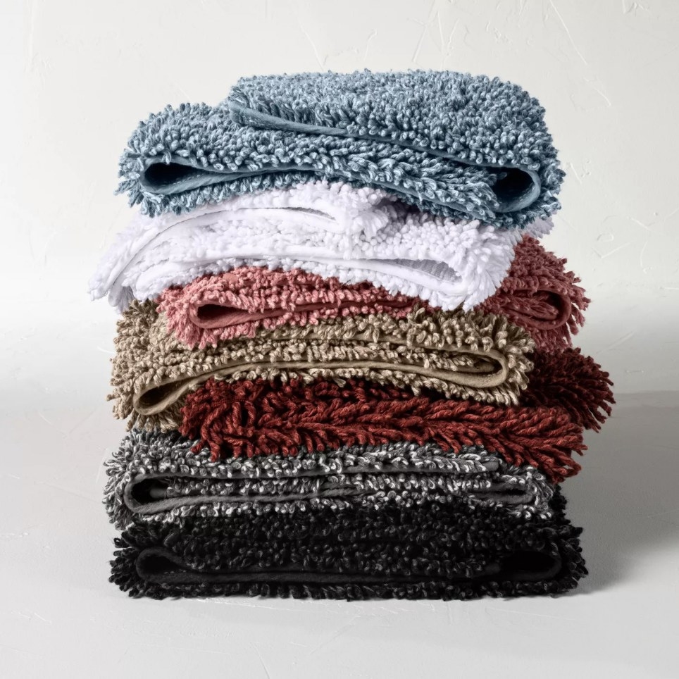 Stacked bath rugs, blue, white, pink, brown, red, gray and black