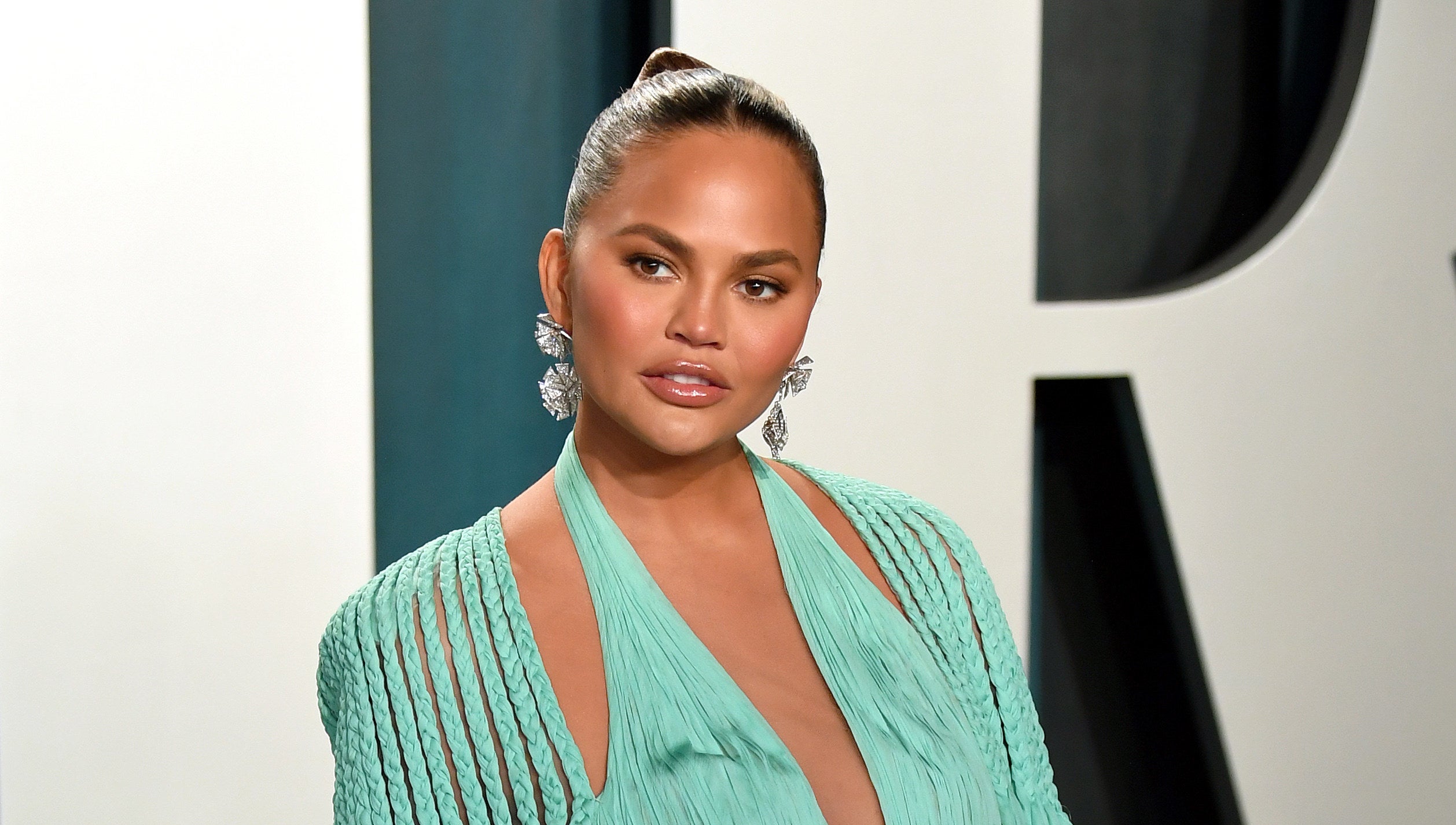 Photo of Chrissy Teigen in a seafoam green dress looking at something off-camera
