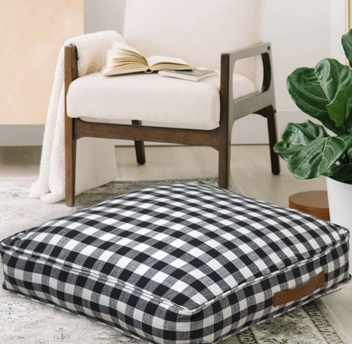 The black gingham floor pillow has a brown handle