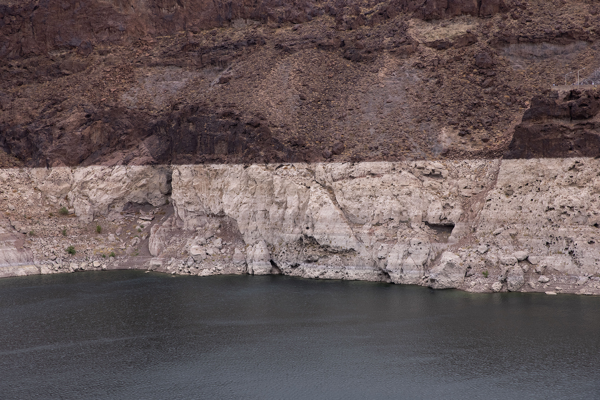 Dropped water levels reveal a lighter shade of rock in a dam